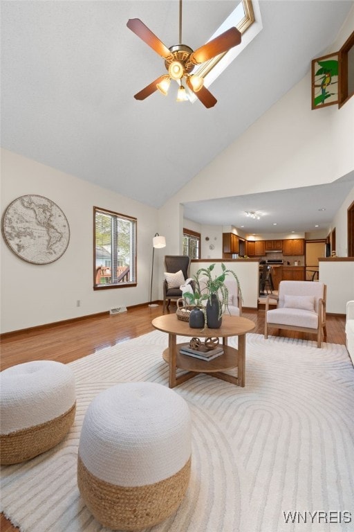 living area featuring a ceiling fan, light wood-style flooring, and high vaulted ceiling