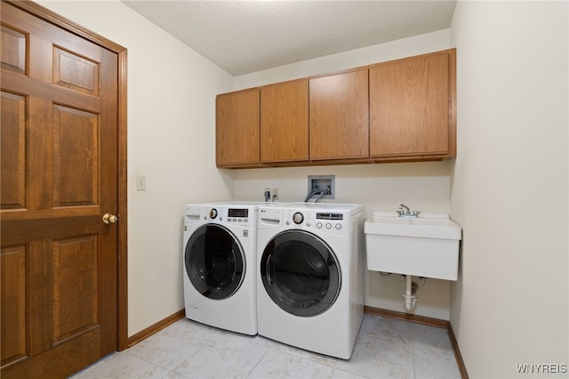 laundry room featuring separate washer and dryer, a sink, cabinet space, and baseboards