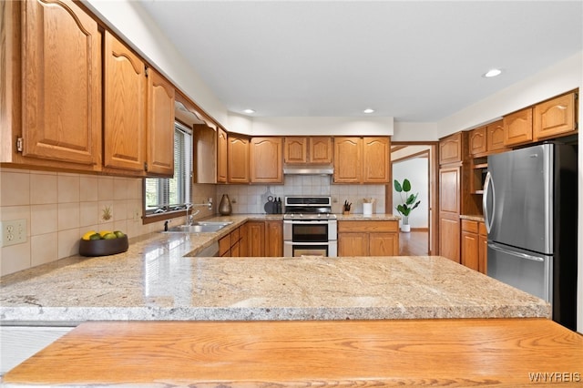kitchen with light countertops, under cabinet range hood, tasteful backsplash, a sink, and stainless steel appliances