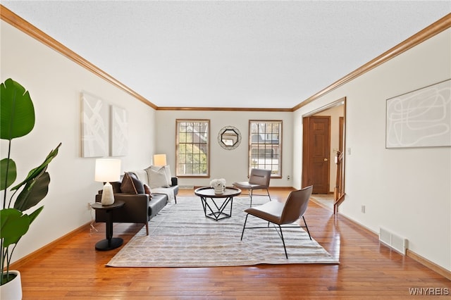 living area featuring crown molding, baseboards, visible vents, and hardwood / wood-style flooring
