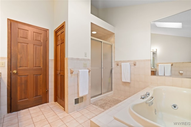 bathroom featuring a whirlpool tub, tile patterned flooring, a shower stall, and tile walls