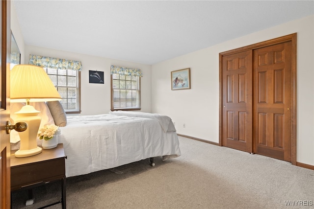 carpeted bedroom with baseboards and a closet