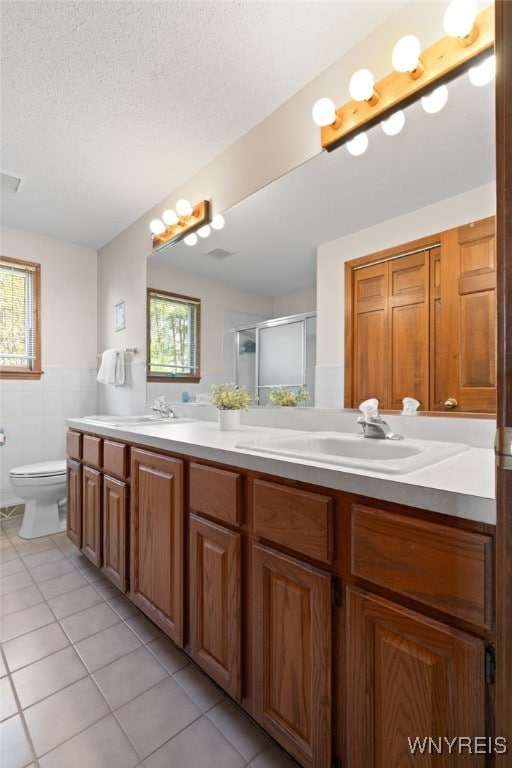 full bath featuring tile patterned floors, tile walls, plenty of natural light, and a sink
