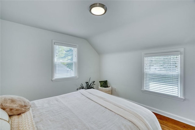 bedroom with baseboards, wood finished floors, and vaulted ceiling