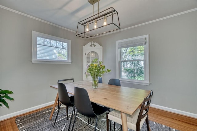 dining room with an inviting chandelier, baseboards, ornamental molding, and wood finished floors