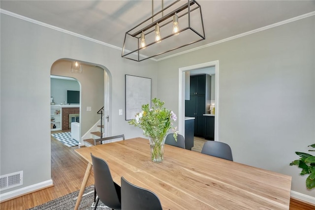 dining space with visible vents, crown molding, and wood finished floors