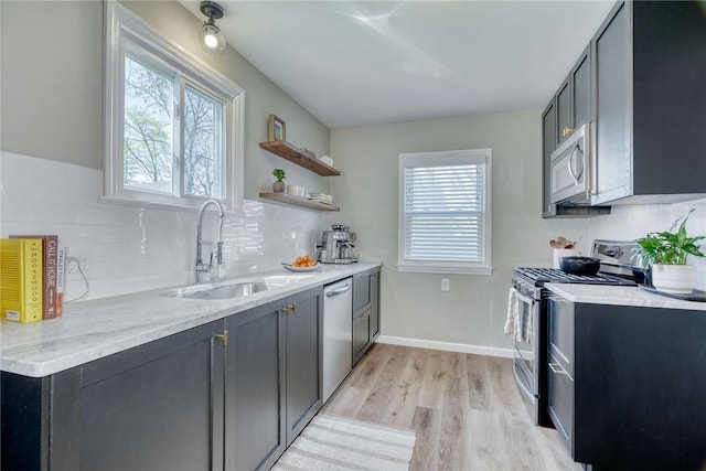 kitchen with a sink, appliances with stainless steel finishes, light wood-style flooring, and a wealth of natural light