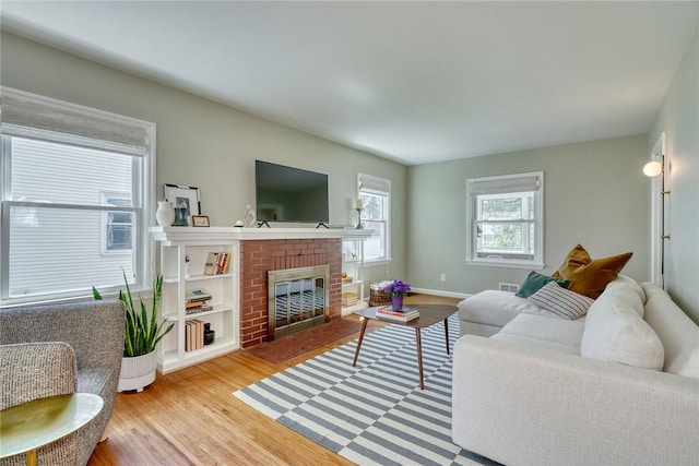 living room featuring visible vents, light wood-style flooring, baseboards, and a fireplace