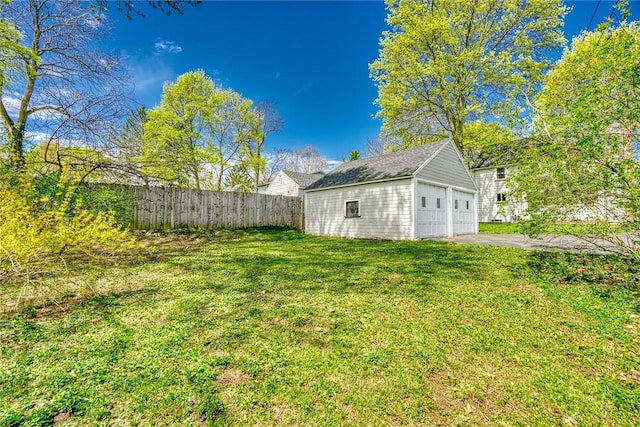 view of yard with fence, an outbuilding, and a garage