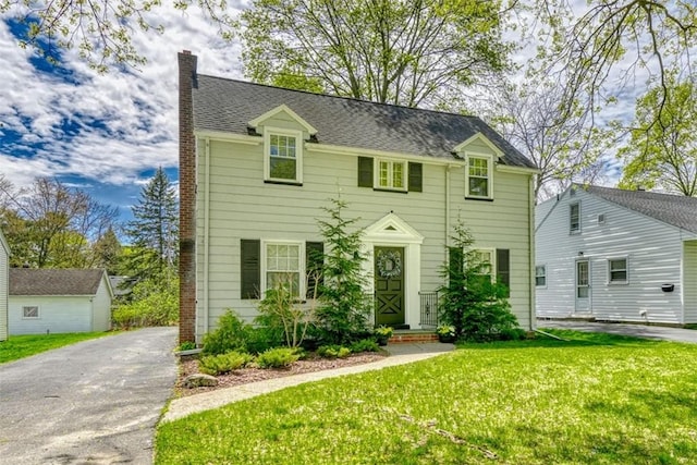 colonial home featuring a front lawn, aphalt driveway, and a chimney