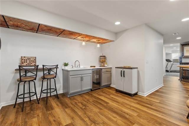 bar with a sink, indoor wet bar, beverage cooler, and wood finished floors