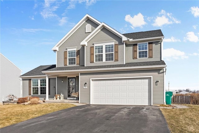 traditional-style home with a porch, driveway, a front yard, and a garage