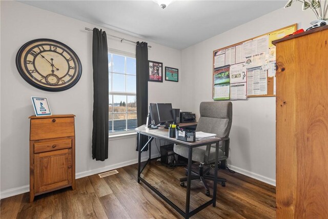 office space with baseboards, visible vents, and wood finished floors