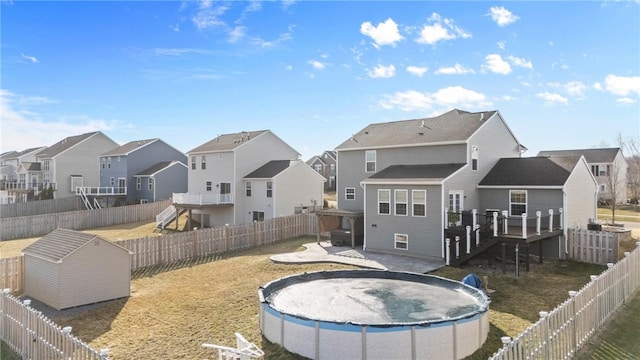 rear view of property with a residential view, a fenced in pool, a fenced backyard, and a storage shed