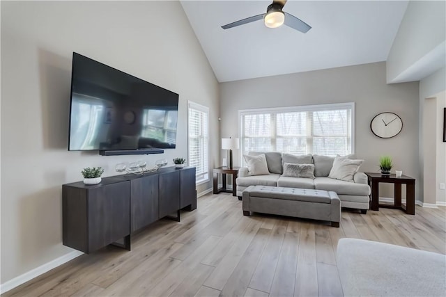 living room featuring ceiling fan, baseboards, light wood finished floors, and high vaulted ceiling
