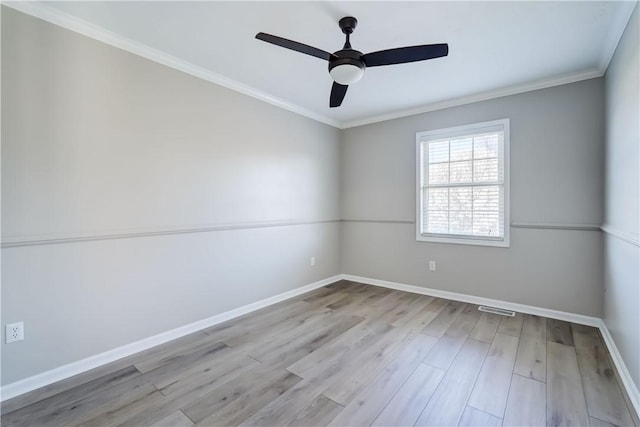 spare room with visible vents, ornamental molding, wood finished floors, baseboards, and ceiling fan
