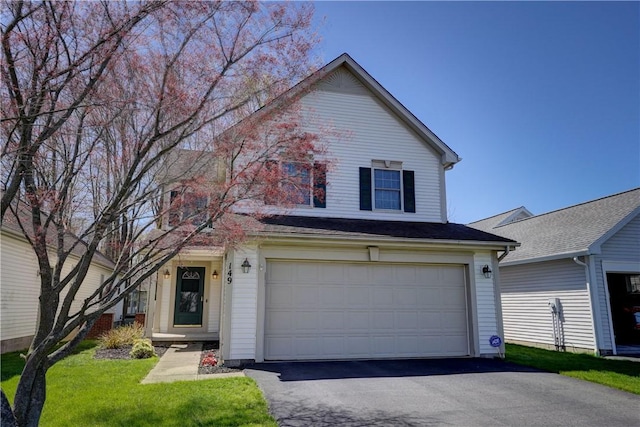traditional home with an attached garage, a front lawn, and aphalt driveway