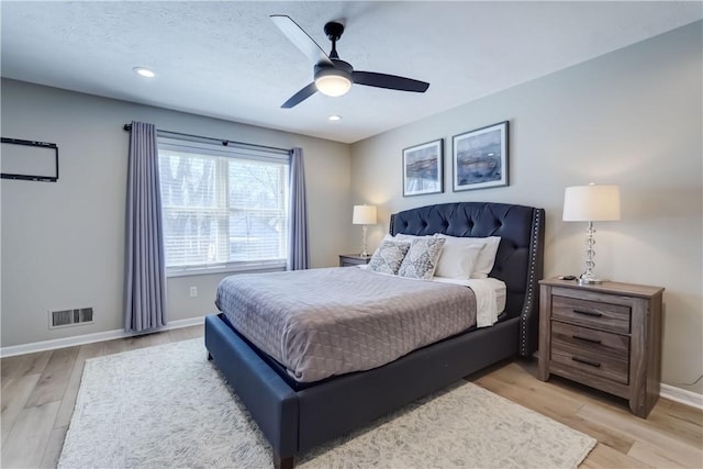 bedroom featuring a ceiling fan, baseboards, visible vents, and light wood-style floors