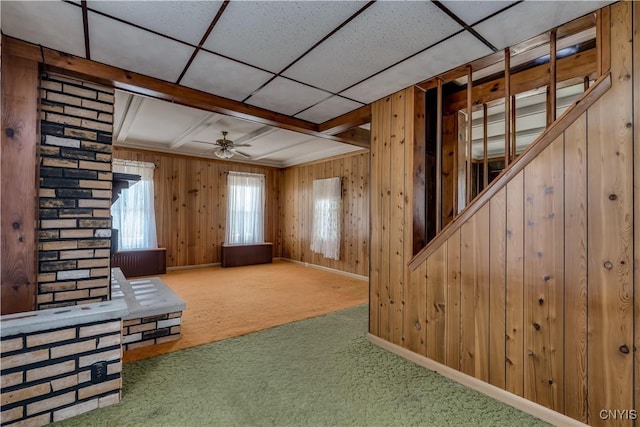 427 S James St, Wilna, NY 13619 - unfurnished living room featuring wooden walls, a ceiling fan, and carpet flooring