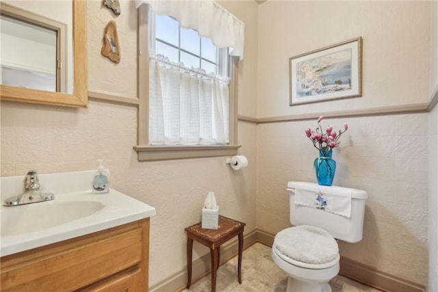 half bathroom featuring vanity, toilet, and tile walls