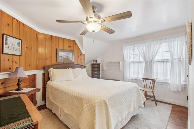bedroom with a ceiling fan, vaulted ceiling, and light wood-style floors