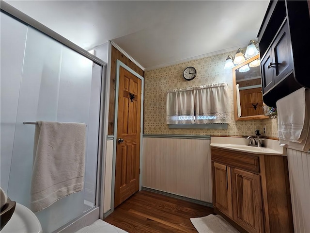 full bath with a shower stall, vanity, a wainscoted wall, ornamental molding, and wallpapered walls