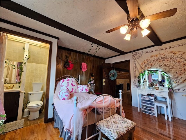 bedroom featuring beamed ceiling, a textured ceiling, and wood finished floors