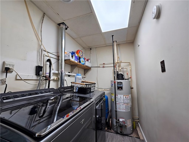laundry area featuring laundry area, baseboards, water heater, and washing machine and dryer