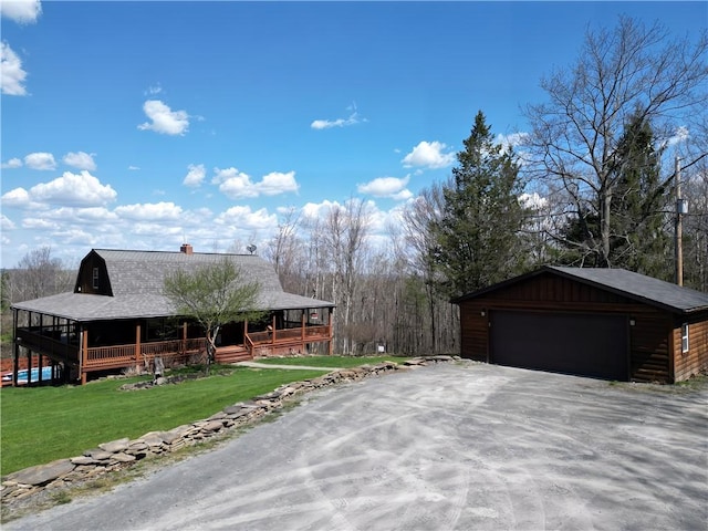 view of side of home featuring a detached garage, a porch, a chimney, an outdoor structure, and a yard