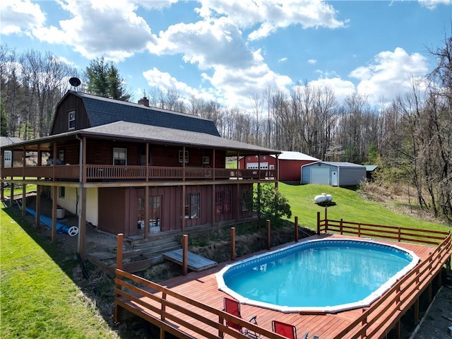 pool with a yard, a deck, and an outbuilding