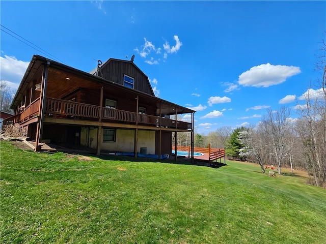 back of house with a yard, a wooden deck, and a gambrel roof