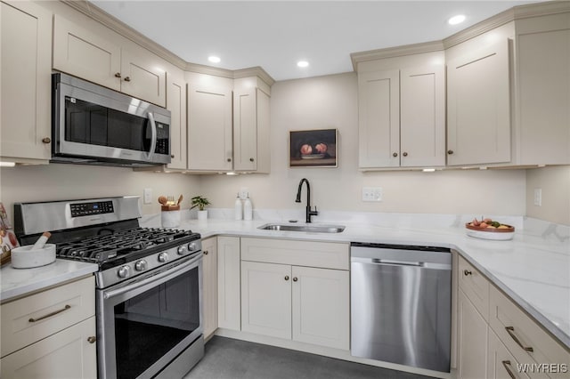 kitchen featuring cream cabinets, appliances with stainless steel finishes, light stone counters, a sink, and recessed lighting