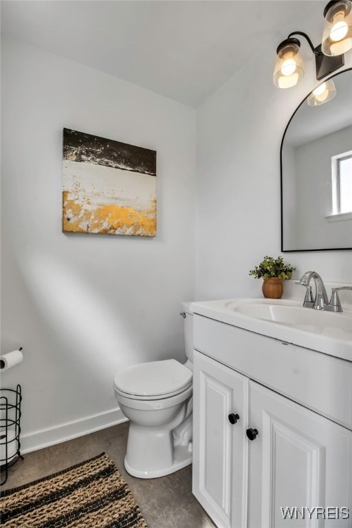 bathroom with toilet, baseboards, and vanity