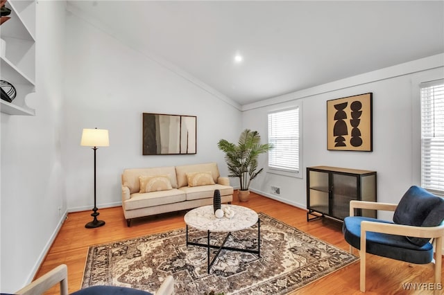 living room with baseboards, vaulted ceiling, wood finished floors, and a wealth of natural light