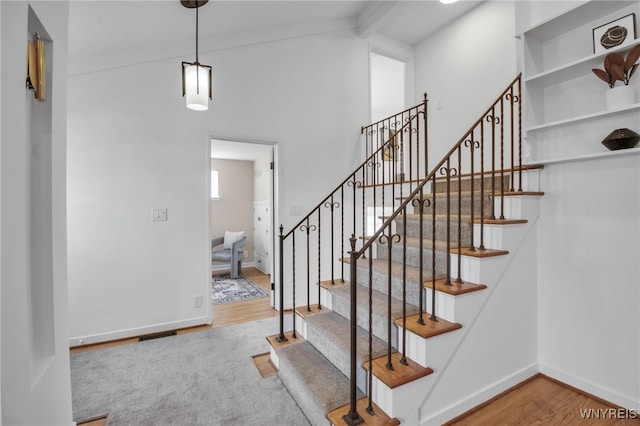 staircase featuring vaulted ceiling with beams, baseboards, and wood finished floors
