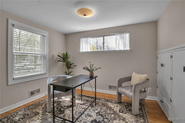 office area with baseboards, wood finished floors, and visible vents