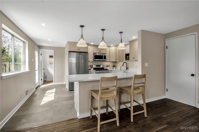 kitchen with a sink, a breakfast bar area, stainless steel appliances, recessed lighting, and a peninsula