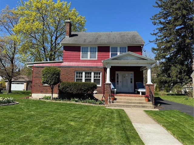 bungalow featuring a chimney, brick siding, a front yard, and a porch