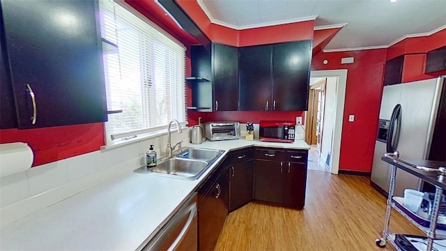 kitchen featuring crown molding, appliances with stainless steel finishes, a sink, light wood finished floors, and light countertops