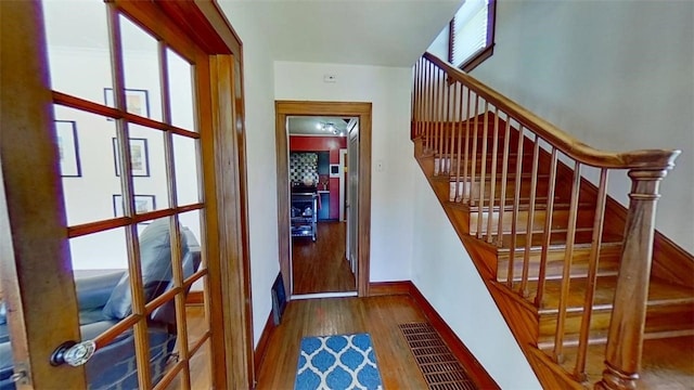 stairway with baseboards, plenty of natural light, and wood finished floors