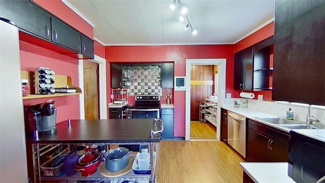 kitchen featuring appliances with stainless steel finishes, a sink, light countertops, light wood-style flooring, and ornamental molding