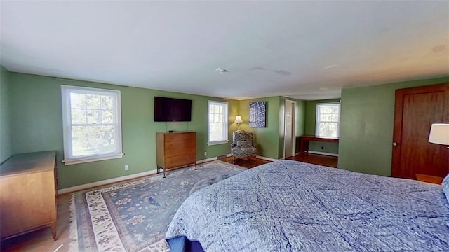 bedroom with baseboards, multiple windows, and wood finished floors