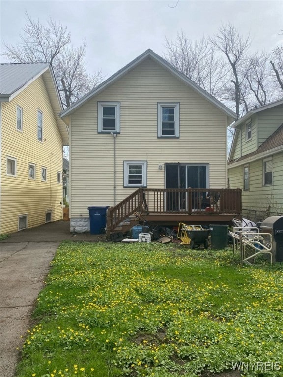 rear view of property featuring a lawn and a deck