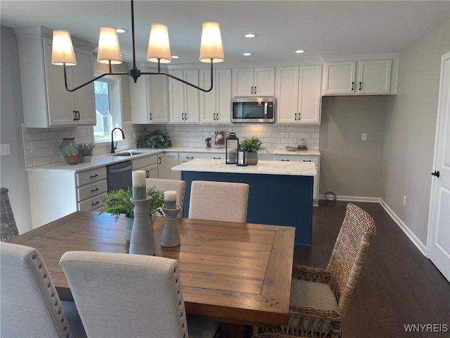 kitchen with baseboards, a center island, light countertops, stainless steel microwave, and a sink
