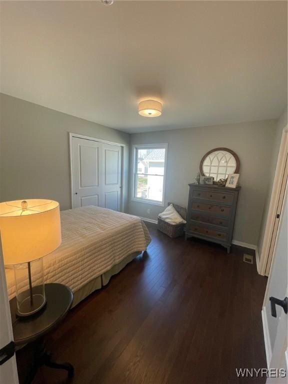 bedroom with baseboards, a closet, and dark wood-style floors