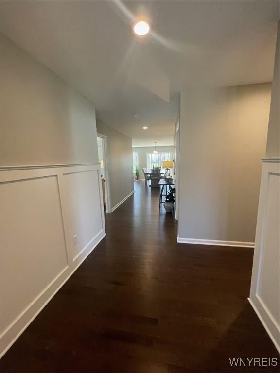 corridor with baseboards, recessed lighting, dark wood finished floors, and a chandelier