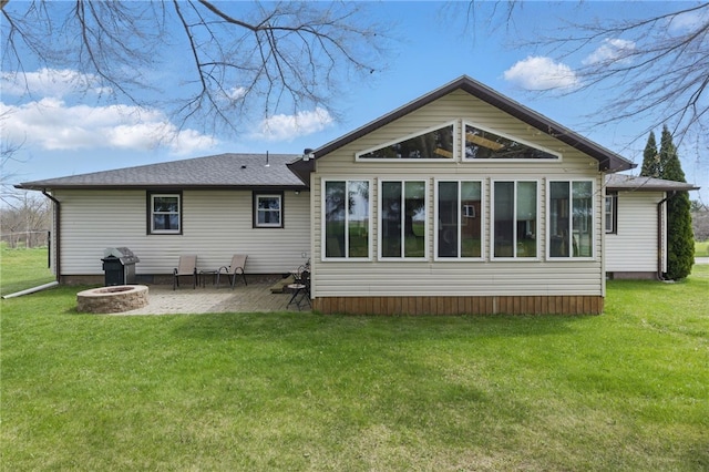rear view of property featuring a lawn, a patio, and an outdoor fire pit