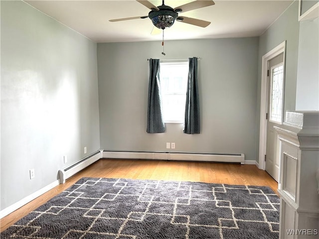 empty room featuring baseboards, a ceiling fan, wood finished floors, and a wealth of natural light