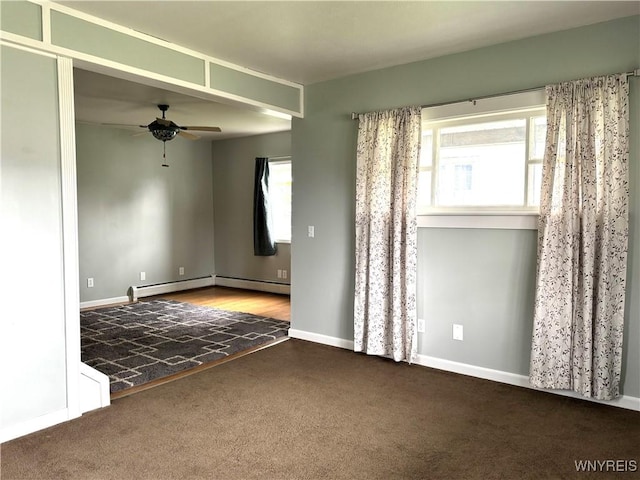 spare room with carpet flooring, baseboard heating, ceiling fan, and a healthy amount of sunlight