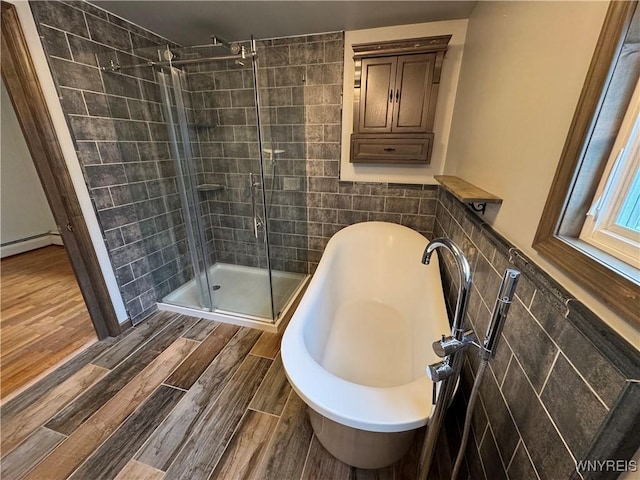 full bathroom featuring a freestanding bath, tile walls, a shower stall, wood finished floors, and a baseboard heating unit